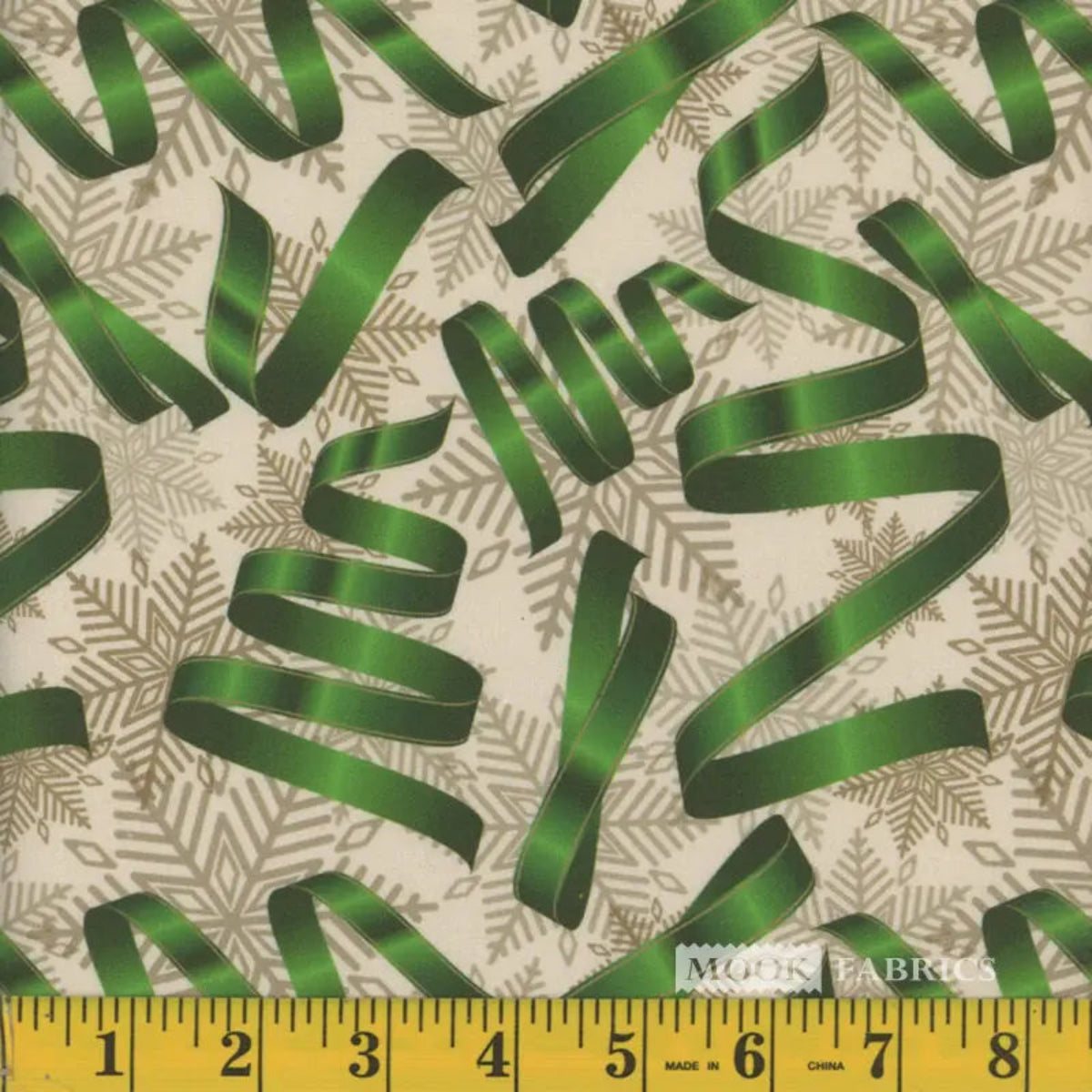 A yardstick showing the width of fabric, which is 44 inches, with a Christmas-themed pattern of green ribbons and silver snowflakes displayed on the fabric.