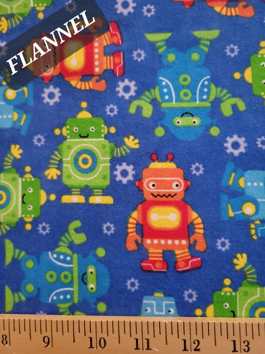 Flannel fabric with colorful robot pattern on a blue background, ruler at the bottom for scale.
